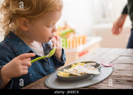 Kaukasische Mädchen Essen mit den Fingern und Löffel Stockfoto