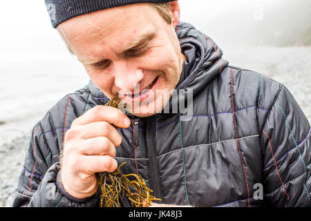 Kaukasischen Mann beißt Algen in der Nähe von Meer Stockfoto