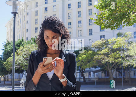 Gemischte Rennen Geschäftsfrau SMS auf Handy im freien Stockfoto