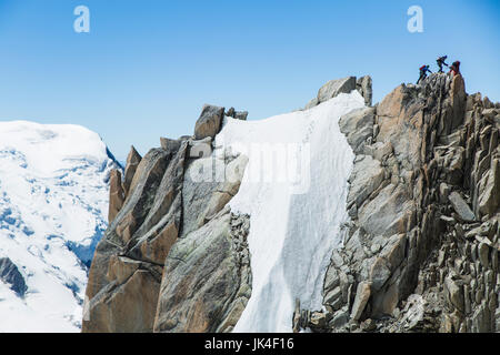 Bergsteiger klettern einen hohen Stein Höhepunkt umgeben von Eis und Schnee mit einem Gletscher im Hintergrund am Mont Blanc Stockfoto