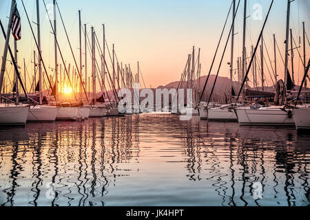 Schöne Segelboote vor Anker auf der Anklagebank, herrliche Aussicht auf die wunderschöne weiße Segelboote über Berge Hintergrund in milden Sonnenuntergang Licht, Luxus Sommer vacati Stockfoto