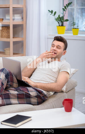 Faulen Mann auf der Couch liegen und Gähnen. Stockfoto