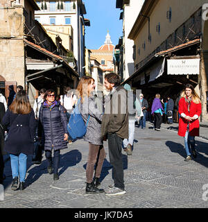 Florenz, Italien: November 2016: Zwei Personen Hug auf der berühmten Ponte Vecchio, während andere Touristen zu Fuss. Stockfoto