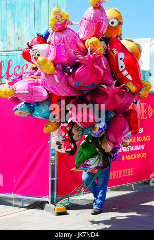 Mann hält und von einer großen Menge Helium Luftballons auf Pier Head Village, Liverpool, UK ausgeblendet Stockfoto