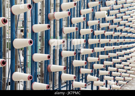 große Gruppe von Spule Gewinde Kegel auf eine Schärmaschine in einer Textilfabrik. Stockfoto