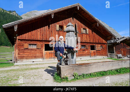 Mann mit Zwergschnauzer, Schwarz-Silber, am Holz Brunnen und Hütte, Grosser Ahornboden, Karwendel parken, Eng-Tal, Tirol, Österreich Stockfoto