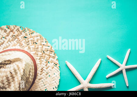 Sommer Urlaub Hintergrund. Strohhut und Seesterne auf blauem Hintergrund. Draufsicht mit Textfreiraum, flach zu legen. Pastell Farbfilter. Stockfoto