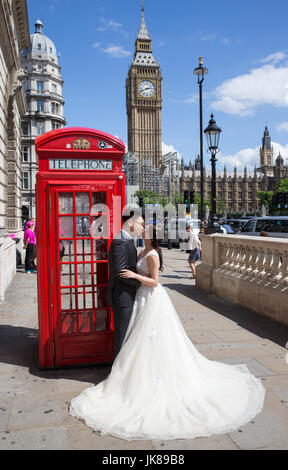 Ein chinesisches Ehepaar posieren für Fotos von einem ikonischen rote Telefonzelle mit Big Ben im Hintergrund, wie sie ihre Flitterwochen in London feiern Stockfoto