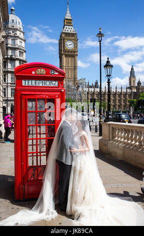 Ein chinesisches Ehepaar posieren für Fotos von einem ikonischen rote Telefonzelle mit Big Ben im Hintergrund, wie sie ihre Flitterwochen in London feiern Stockfoto