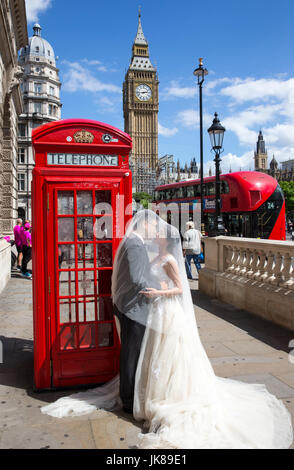 Ein chinesisches Ehepaar posieren für Fotos von einem ikonischen rote Telefonzelle mit Big Ben im Hintergrund, wie sie ihre Flitterwochen in London feiern Stockfoto