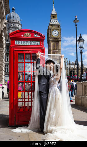 Ein chinesisches Ehepaar posieren für Fotos von einem ikonischen rote Telefonzelle mit Big Ben im Hintergrund, wie sie ihre Flitterwochen in London feiern Stockfoto