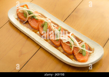 Lachs-Sashimi mit Spargel und Zwiebel auf Teller, bereit um zu essen. Stockfoto