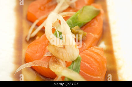 Lachs-Sashimi mit Spargel und Zwiebel auf Teller, bereit um zu essen. Stockfoto