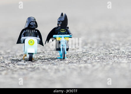 LEGO Batman und Darth Vader zusammen mit Fahrrad und Roller fahren. Stockfoto