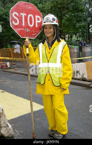 Eine hübsche junge Dame, die eine Flagger auf ein Bautrupp hält ein Stoppschild Newar Washington Square Park in Manhattan, New York City. Stockfoto