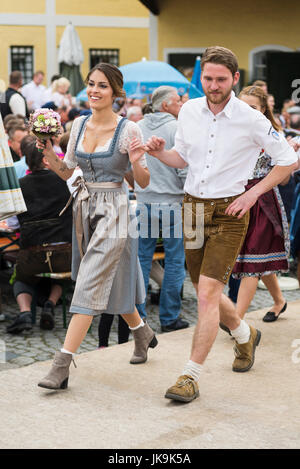 Junge bayerische paar in traditionellen Dirndl Kleid und Lederhosen Durchführung traditionellen Volkstanz Bandltanz rund um den Maibaum Stockfoto