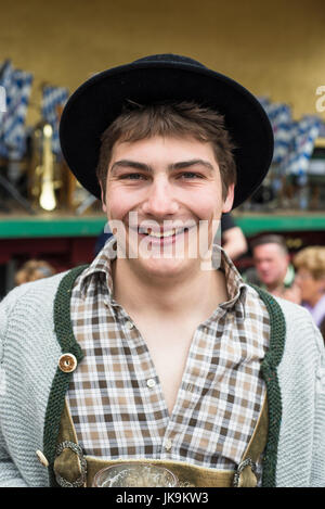 Porträt eines lächelnden jungen bayerischen Mannes in bayrischer Tracht mit Lederhosen, Filz schwarz, Hut, graue Strickjacke, braun kariertes Hemd Stockfoto