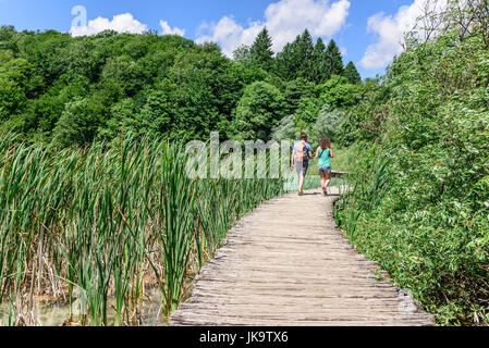 Touristen zu Fuß entlang der Holzstege in Nationalpark Plitvicer Seen, Kroatien. Stockfoto