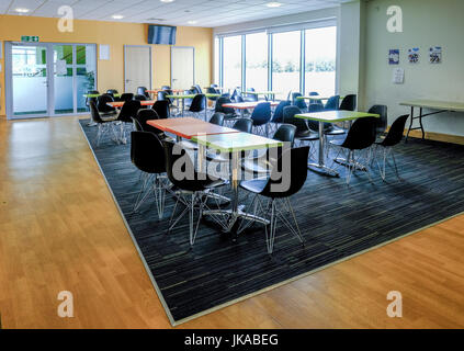 Essex, England UK-12 Juni, 2017:Empty Kantine mit Tischen und Stühlen.  Helle und luftige Zimmer mit Licht durch die großen Fenster. Stockfoto