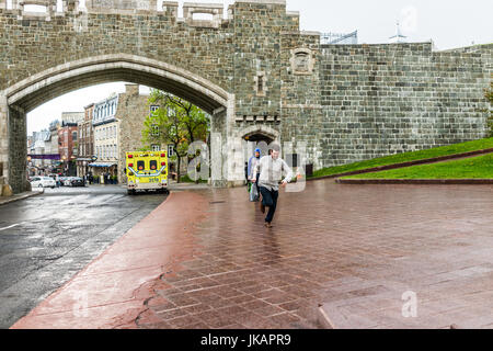 Quebec Stadt, Kanada - 31. Mai 2017: Saint John's Gate Festung Eingang zur Altstadt Straße mit junger Mann läuft im strömenden Regen Stockfoto