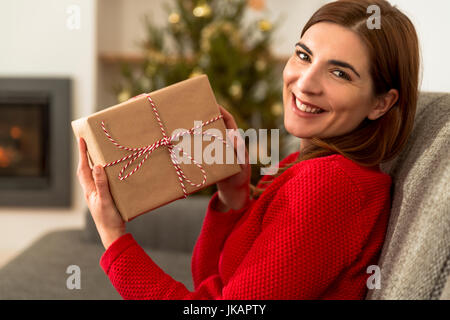 Schöne glückliche Frau zu Hause halten Weihnachtsgeschenke Stockfoto