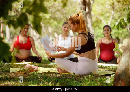 Schwangere Frauen, die pränatale Lektion im Park. Lehrer erklärt Wachstum des Babys im Bauch mit Bildern und Zeichnungen. Stockfoto