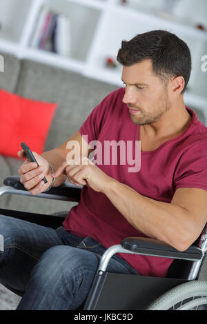 kreative Geschäftsmann im Rollstuhl hält eine Telefon im Büro Stockfoto