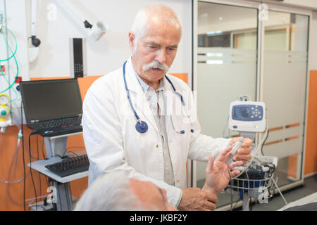 Leitender Arzt Patienten Hand Pulsoximeter aufsetzen Stockfoto