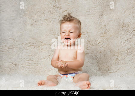 schreiendes Baby junge in Windeln, sitzen auf eine zottige hausgemachte Wolldecke Stockfoto