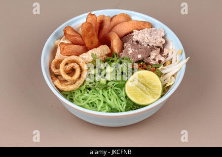 Grüne Nudeln mit Tom Yam überstiegen gehackt Schweinefleisch, Huhn Leber, gebratene Wurst, Zitrone, Sojasprossen, Chili, Schwarten und Koriander zu halbieren. Stockfoto