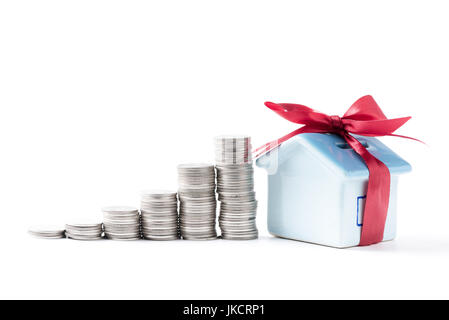 Haus-Sparschwein mit Münzen gestapelt in isolierten weißen Hintergrund. sparen Geld für Haus-Konzept. Stockfoto
