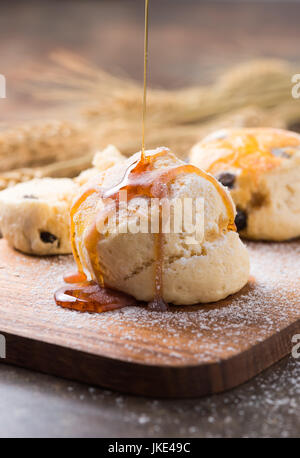 Traditionelle köstliche britische Gebäck und Wüste - Scones und Honig auf Top und hölzernen Hintergrund Stockfoto