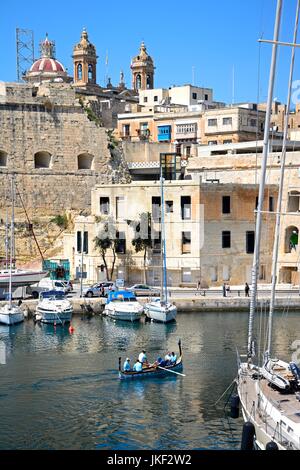 Passagiere an Bord einer traditionellen maltesischen Dghajsa Wassertaxi im Hafen mit Blick auf Senglea Waterfront, Vittoriosa, Malta, Europa. Stockfoto