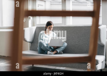 Yung Frau in Ihrer neuen Wohnung sitzen mit einem Laptop Stockfoto