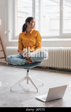 Yung Frau in Ihrer neuen Wohnung sitzen mit einem Laptop Stockfoto