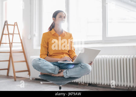 Yung Frau in Ihrer neuen Wohnung sitzen mit einem Laptop Stockfoto