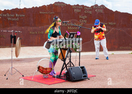 Serenity Sam von Cosmic Chords, singend mit Mikrofon. Im Juli treffen sich auf der Morecambe Promenade Multi-Instrument-One-man-Bands aus dem ganzen Land zu einem unterhaltsamen, kostenlosen Festival mit musikalischem Chaos. Diese ein-Frauen-Band hat einen besonderen Platz in der Phantasie aller und diese Feier der musikalischen Koordination ist ein einzigartiges Ereignis, das die Phantasie der Menschen, unabhängig von ihrem Alter, anzieht. Einmal gesehen nie vergessen. Bands gibt es in allen Formen und Größen, spielen Musik aus jedem Genre. Stockfoto