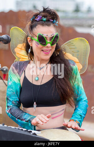 Serenity Sam von Cosmic Chords, singend mit Mikrofon. Im Juli treffen sich auf der Morecambe Promenade Multi-Instrument-One-man-Bands aus dem ganzen Land zu einem unterhaltsamen, kostenlosen Festival mit musikalischem Chaos. Diese ein-Frauen-Band hat einen besonderen Platz in der Phantasie aller und diese Feier der musikalischen Koordination ist ein einzigartiges Ereignis, das die Phantasie der Menschen, unabhängig von ihrem Alter, anzieht. Einmal gesehen nie vergessen. Bands gibt es in allen Formen und Größen, spielen Musik aus jedem Genre. Stockfoto