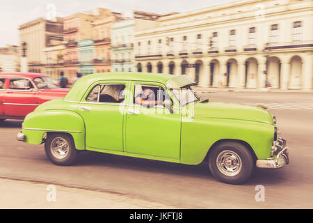 Grüne amerikanische Oldtimer mit jungen Kubaner fahren in Alt-Havanna, panning shot Stockfoto