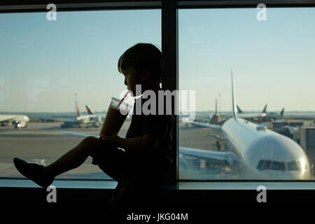New York City, Vereinigte Staaten, JFK Airport Jungfrau ein kleiner Junge Passagier als die Getränke aus dem Fenster Stockfoto