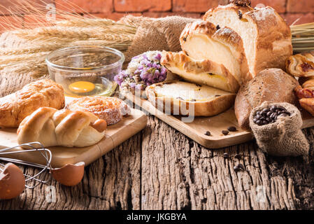Auswahl an Brot und Weizen auf Holztisch Hintergrund, hausgemachte Backwaren Stockfoto