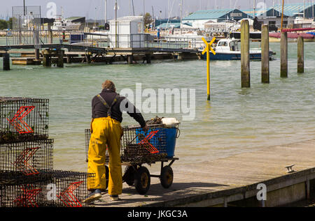 Ein Crew-Mitglied schiebt einen Buggy auf einem schwimmenden Ponton am Hafen in Warsash in Hampshire, da er hilft, ein Trawler entladen Stockfoto