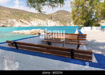 Bänke und Tisch mit Blick auf Bucht in Mandrakia Dorf. Insel Milos, Griechenland. Stockfoto