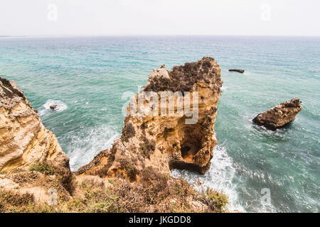 Reisen Sie nach atemberaubenden Felsen Klippen mit Meere Höhlen am Strand von sandigen Camilo in bunten sonnigen blauen Himmel. Sommer Berufung. Stockfoto