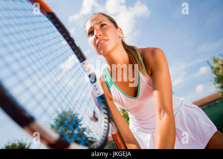 Hübsche junge Frau, die Tennis spielen, an einem sonnigen Tag Stockfoto