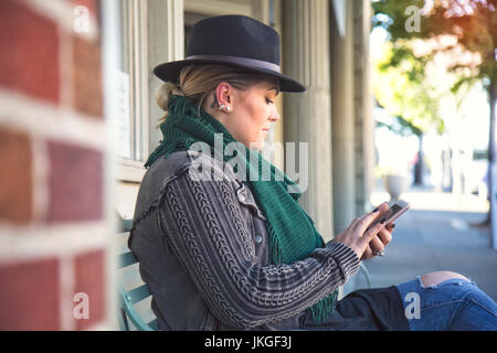 Eine modische, 30-etwas Frau Texte auf einem mobilen Gerät Stockfoto