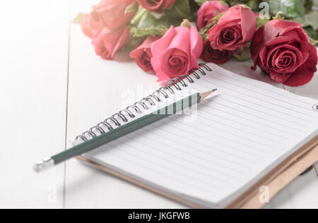 leeres Notizbuch mit Bleistift und rote Rose auf weißem Holz Hintergrund, selektiven Fokus Stockfoto