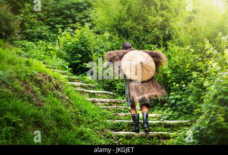 Chinesische Bauern tragen eine antike Regenmantel Treppensteigen Stockfoto