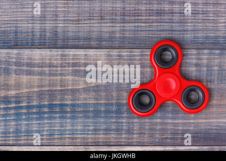 Ein roter Zeiger Spinner liegt auf einem Holztisch. Es gibt Platz für Text auf der linken Seite Stockfoto