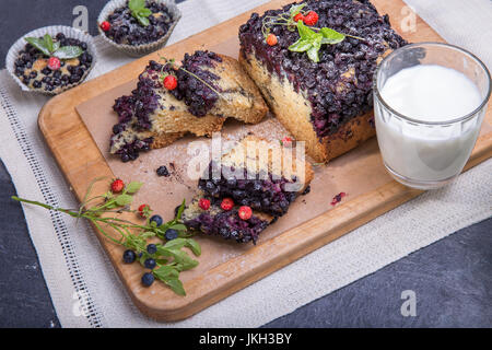 Beeren-Kuchen und Muffins mit Heidelbeeren und Erdbeeren auf einem Teller grün und ein Schreibtisch aus Holz mit Milch serviert und und frischen Beeren Stockfoto